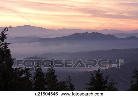 Sunrise over Tiber valley with grey pink and golden sky in the early morning mist of winter, with tree outline in foreground, and hilltop town of Todi in distance View Large Photo Image Stock Photograph - Sunrise over Tiber valley with grey pink and golden sky in the early morning mist of winter, with tree outline in foreground, and hilltop town of Todi in distance. Fotosearch