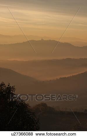 Sunrise over Tiber valley with orange and golden sky in the early morning mist of winter, with tree outline in foreground, and hilltop town of Todi in distance View Large Photo Image Stock Photo - Sunrise over Tiber valley with orange and golden sky in the early morning mist of winter, with tree outline in foreground, and hilltop town of Todi in distance. Fotosearch