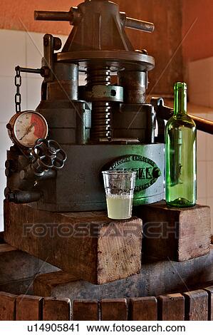 Stock Image - Traditional wooden barrel grape press with manometer, glass of grape juice and bottle. Fotosearch