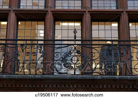 Stock Photo - Upward view of sandstone facade fronted with ornamental wrought iron railing and lead glass windows, interior lights on, Glasgow, Scotland. Fotosearch