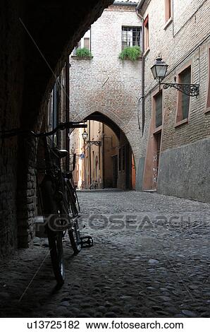 Stock Image - view of 14th century street with Gothic arches and cobblestone paving, bicycle parked in foreground. Fotosearch