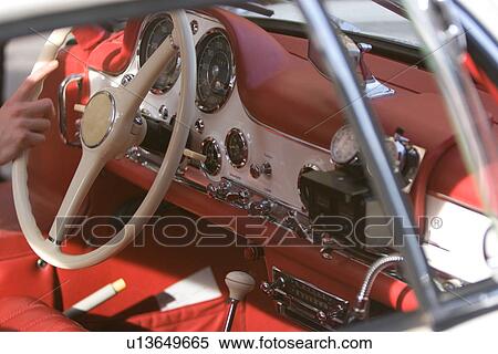 Stock Photography - View of interior with red and white trim, hand on white steering wheel. Fotosearch