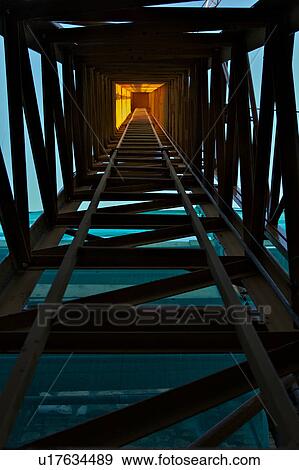 Stock Photo - View of metal structure, looking up building crane to sunlight above. Fotosearch