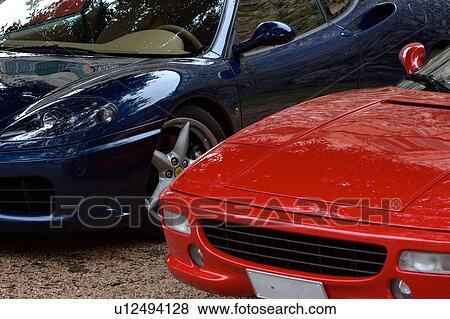 Stock Photo - View of parked red and blue Ferraris, front quarter view, on cloudy rainy day. Fotosearch