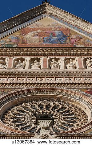 View of Rose window, ornate sculpture and decoration of facade of Orvieto Duomo, with Coronation of the Virgin mosaic, and blue summer afternoon sky above View Large Photo Image Picture - View of Rose window, ornate sculpture and decoration of facade of Orvieto Duomo, with Coronation of the Virgin mosaic, and blue summer afternoon sky above. Fotosearch