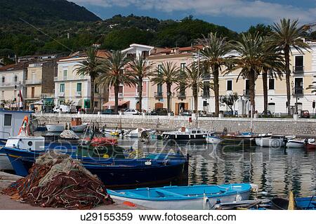 Stock Photo -  View of Scario harbour with small fishing boats moored, and town of Scario, with hills beyond, on sunny, summer morning. Fotosearch