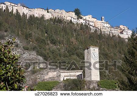 view upward of hilltop town of Borgo Cerreto, with old clock tower and green trees on slopes below, against blue sunny winter sky View Large Photo Image Stock Image - view upward of hilltop town of Borgo Cerreto, with old clock tower and green trees on slopes below, against blue sunny winter sky. Fotosearch
