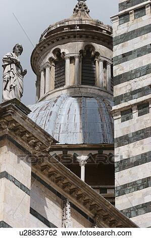 View upwards of Siena Duomo main dome with edge of black and white striped campanile, and statue of saint, against stormy gray sky in sunlight View Large Photo Image Stock Image - View upwards of Siena Duomo main dome with edge of black and white striped campanile, and statue of saint, against stormy gray sky in sunlight. Fotosearch