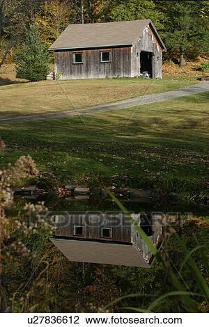Stock Image - Wooden shed with reflection in pond, Fall, Vermont, USA. Fotosearch