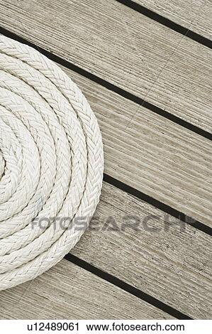 Stock Image - Close-up of a curled up rope on the deck of a sailboat. Fotosearch