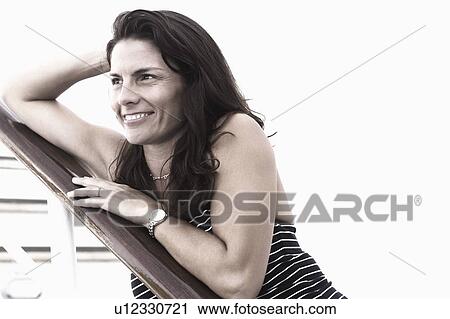 Close-up of a mid adult woman leaning against a banister and smiling View Large Photo Image Stock Image - Close-up of a mid adult woman leaning against a banister and smiling. Fotosearch