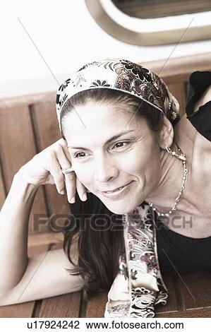 Close-up of a mid adult woman lying on a bench and smiling View Large Photo Image Stock Image - Close-up of a mid adult woman lying on a bench and smiling. Fotosearch