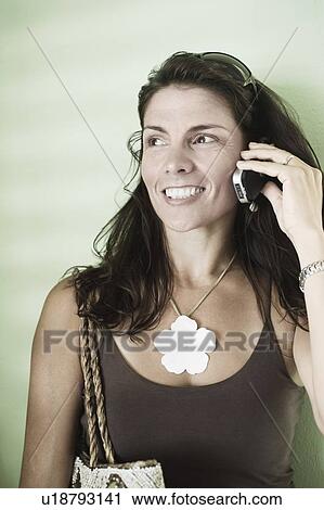Close-up of a mid adult woman talking on a mobile phone and smiling View Large Photo Image Stock Image - Close-up of a mid adult woman talking on a mobile phone and smiling. Fotosearch