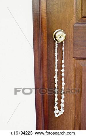 Stock Image - Close-up of a necklace hanging on a doorknob. Fotosearch