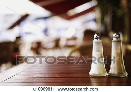 Stock Image - Close-up of a salt shaker and a pepper shaker on a table. Fotosearch