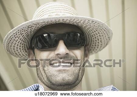 Close-up of a young man wearing a straw hat and sunglasses View Large Photo Image Stock Photo - Close-up of a young man wearing a straw hat and sunglasses. Fotosearch