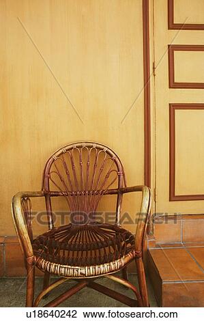 Stock Image - Close-up of an armchair in front of a house. Fotosearch