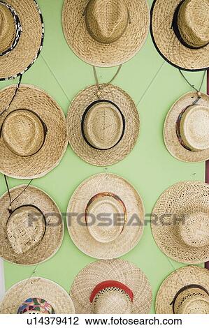Stock Image - Close-up of straw boater hats hanging on the wall. Fotosearch