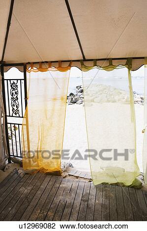 Stock Image - Curtains at the entrance of a beach hut. Fotosearch