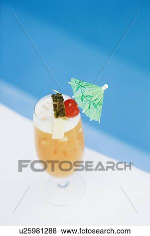 Stock Photo - High angle view of a glass of cocktail at the poolside. Fotosearch