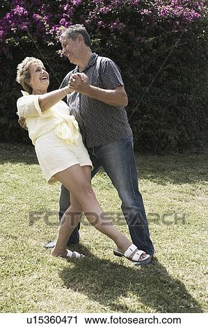 Stock Image - Mature woman and a senior man dancing in a garden. Fotosearch