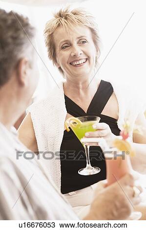 Mature woman and a senior man holding glasses of cocktail and smiling View Large Photo Image Stock Image - Mature woman and a senior man holding glasses of cocktail and smiling. Fotosearch