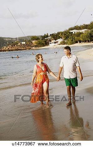 Mature woman holding a senior man's hand and walking on the beach View Large Photo Image Stock Photo - Mature woman holding a senior man's hand and walking on the beach. Fotosearch