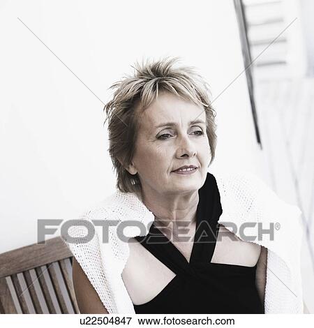 Stock Photo - Mature woman sitting on a chair and smiling. Fotosearch