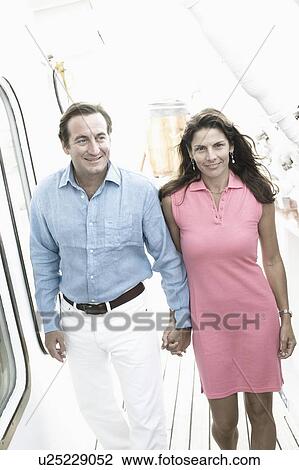Mid adult couple walking with holding hands of each other on the deck of a cruise ship View Large Photo Image Stock Image - Mid adult couple walking with holding hands of each other on the deck of a cruise ship. Fotosearch