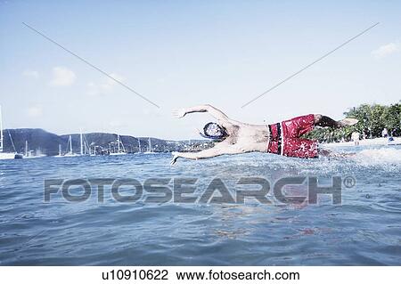 Mid adult man diving in water View Large Photo Image Stock Image - Mid adult man diving in water. Fotosearch