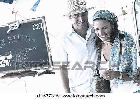 Mid adult man standing with a mid adult woman holding a credit card and smiling View Large Photo Image Stock Photograph - Mid adult man standing with a mid adult woman holding a credit card and smiling. Fotosearch