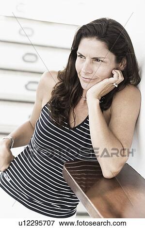 Stock Photo - Mid adult woman smirking with her hand on her chin. Fotosearch