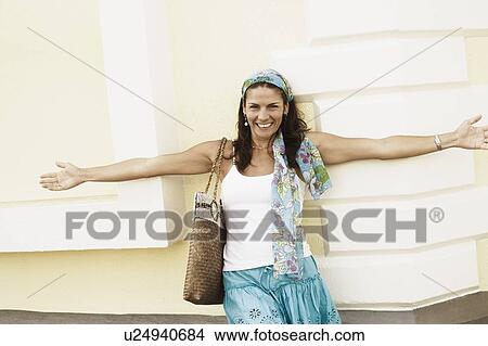 Picture - Portrait of a mid adult woman leaning against a wall and smiling. Fotosearch