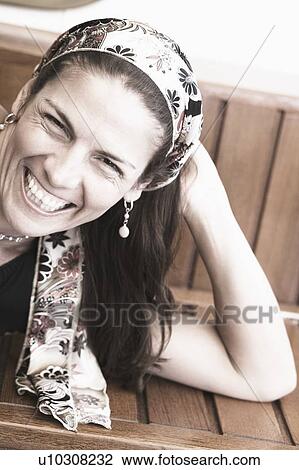 Stock Image - Portrait of a mid adult woman lying on a bench and smiling. Fotosearch