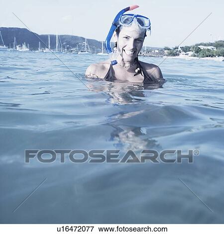 Stock Photo - Portrait of a mid adult woman standing in water and smiling. Fotosearch