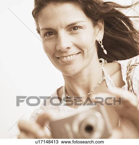Portrait of a mid adult woman taking a picture with a digital camera View Large Photo Image Stock Image - Portrait of a mid adult woman taking a picture with a digital camera. Fotosearch