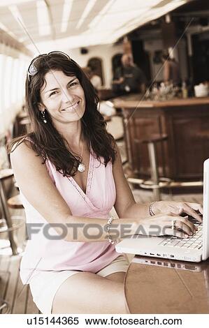 Portrait of a mid adult woman using a laptop and smiling View Large Photo Image Stock Photography - Portrait of a mid adult woman using a laptop and smiling. Fotosearch
