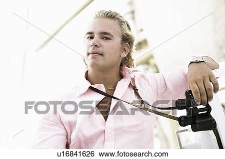Stock Photograph - Portrait of a young man holding binoculars. Fotosearch