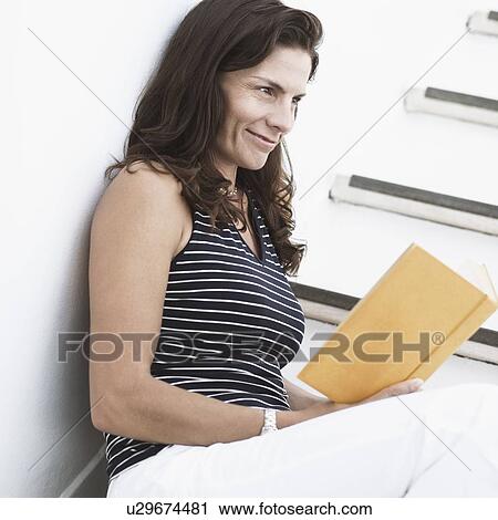 Side profile of a mid adult woman holding a book and smirking View Large Photo Image Stock Image - Side profile of a mid adult woman holding a book and smirking. Fotosearch