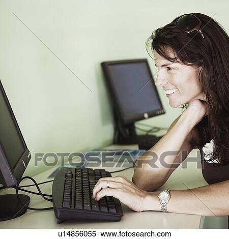 Stock Photography - Side profile of a mid adult woman using a computer. Fotosearch