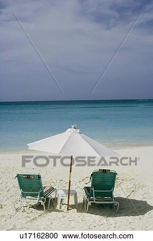 Stock Image - Two empty chairs and a beach umbrella on the beach. Fotosearch