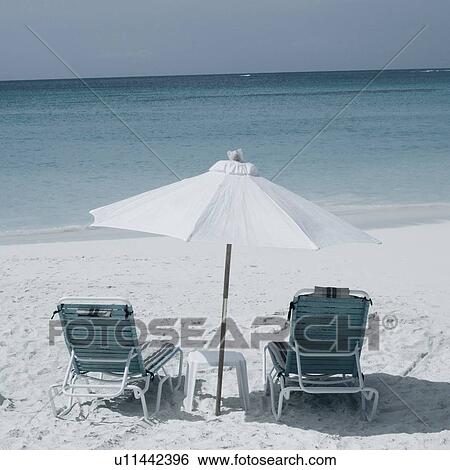 Two empty chairs and a beach umbrella on the beach View Large Photo Image Stock Photograph - Two empty chairs and a beach umbrella on the beach. Fotosearch