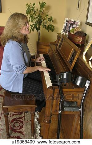 Stock Photo - A woman enjoys playing on the piano.. Fotosearch