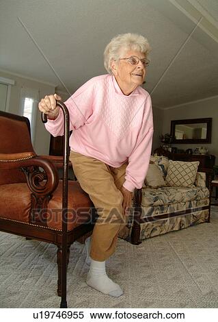 An elderly woman gets up from a break in her living room. View Large Photo Image Stock Photography - An elderly woman gets up from a break in her living room.. Fotosearch