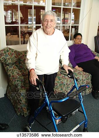 Stock Photograph - An elderly woman walks with a walker.. Fotosearch