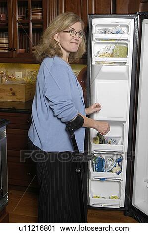 Female with arm crutches looks in refrigerator. View Large Photo Image Stock Image - Female with arm crutches looks in refrigerator.. Fotosearch