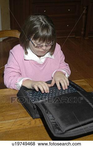 Stock Photo - Girl with Down syndrome sitting at table, typing on a computer keyboard.. Fotosearch