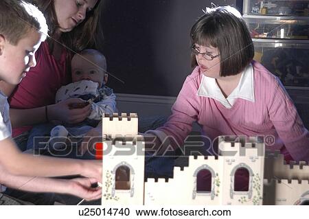 Little boy and a little girl with Down syndrome playing with a castle doll- house while a woman holding a baby watches them. View Large Photo Image Stock Image - Little boy and a little girl with Down syndrome playing with a castle doll- house while a woman holding a baby watches them.. Fotosearch