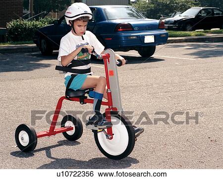 Stock Photograph - Little boy who is blind and has other disabilities riding an adapted tricycle.. Fotosearch