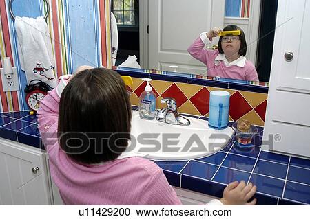 Little girl with Down syndrome combing her hair while looking at her reflection in a mirror. View Large Photo Image Stock Image - Little girl with Down syndrome combing her hair while looking at her reflection in a mirror.. Fotosearch